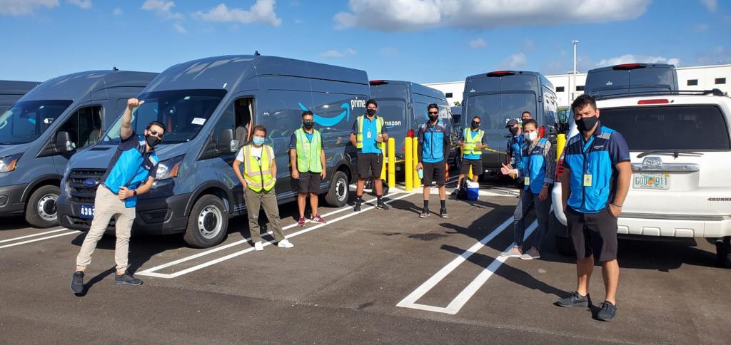 Equipo de conductores de BOOZ frente a las camionetas de reparto